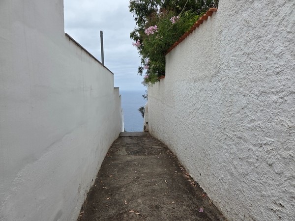 Narrow lane between white walls leading to the start of the cliff stairway Narrow lane between white walls leading to the start of the cliff stairway.