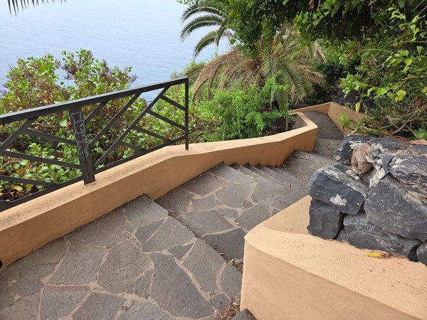 Switchback stairs with metal railings and lush greenery above the ocean Switchback stairs with metal railings and lush greenery above the ocean.