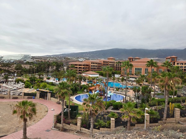 Panoramic look over resort gardens and pools seen from the Mirador de las Palomas, with the mountains of Adeje in the background.