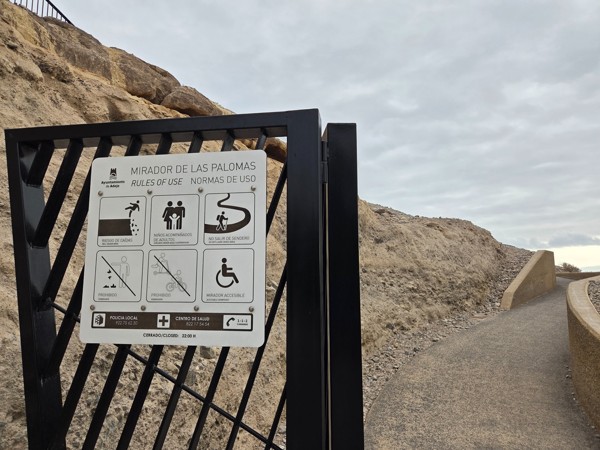 Close view of the Mirador de las Palomas information sign showing rules of use and accessibility icons from the Ayuntamiento de Adeje.