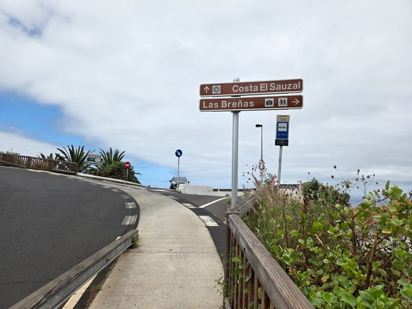 Directional sign at the top of El Sauzal indicating Costa El Sauzal and Las Breñas viewpoint, next to the TITSA bus stop.