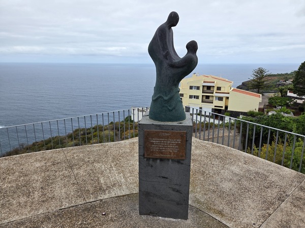 Sculpture honoring the fishermen of El Puertito at the plaza above the cliff, with the ocean behind.