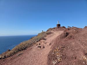 Summit marker at the top of Montaña Roja with a clear sky and ocean background.