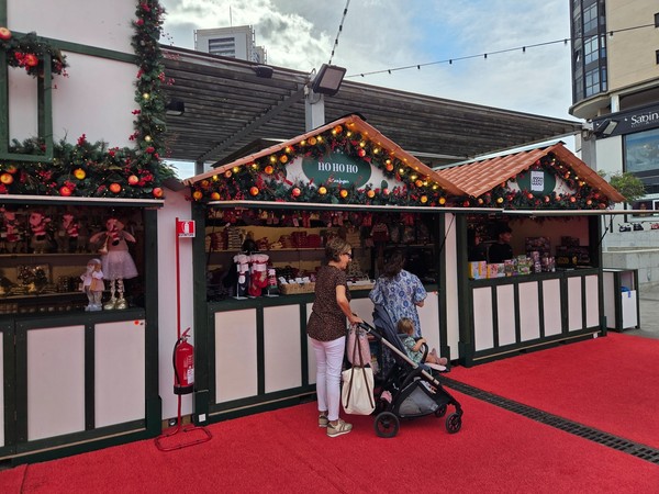Families with children visiting Christmas market stalls labelled Ho Ho Ho and Lego at El Corte Inglés in Tenerife.