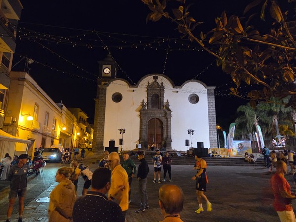 View of the illuminated church of San Pedro Apóstol in Güímar with runners and spectators gathered in the square at night.