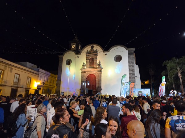 Large crowd gathered in front of the illuminated church of San Pedro during La Nocturna Güímarera at night.