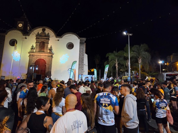 Winners of La Nocturna Güímarera standing on the stage in Plaza de San Pedro while the crowd watches the prize-giving ceremony.