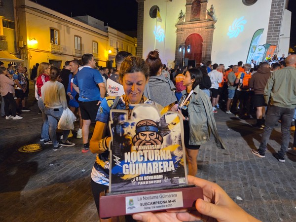 Close-up of a runner holding the La Nocturna Güímarera subchampion trophy in front of the busy square in Güímar.