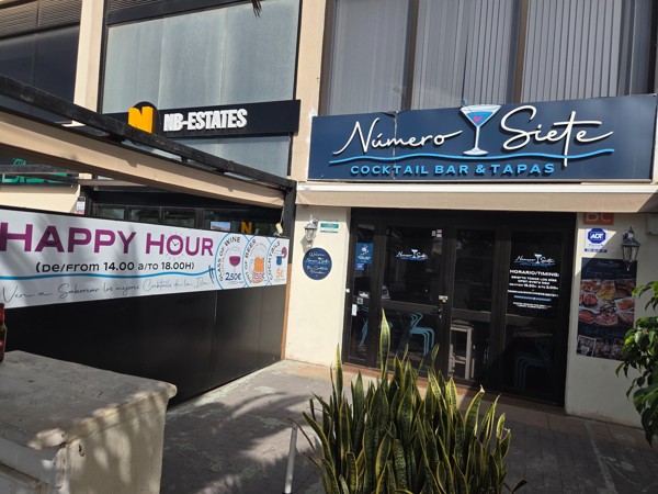 Número Siete cocktail bar and tapas in Palm-Mar with a banner advertising happy hour drinks.
