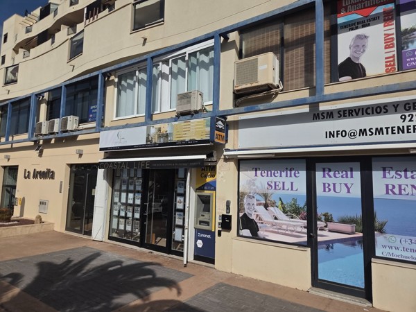 Row of offices in Palm-Mar including Coastal Life real estate and MSM Servicios with signs advertising sell, buy and rent.