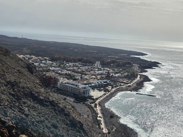 Aerial view of Palm-Mar on the coast of southern Tenerife with the Atlantic Ocean, seafront promenade and apartment complexes along the shore.