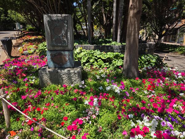 Sculpture surrounded by multicolored flowers in a park corner