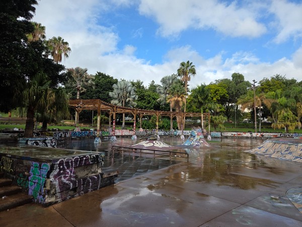 Skatepark zone in Parque La Granja with ramps, graffiti and wooden pergolas surrounded by tropical trees.