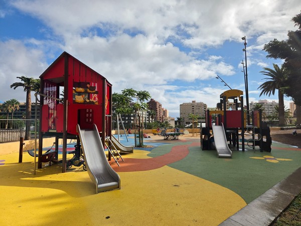Children’s playground in Parque La Granja with colourful rubber floor, slides and play towers under a blue sky.
