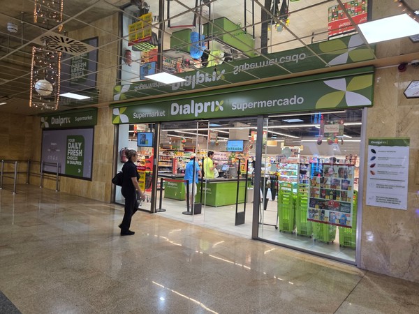 Entrance to Dialprix supermarket inside Pasarela Shopping Center with bright green branding, trolleys and shoppers entering the store.
