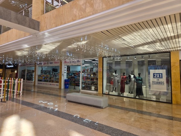 Row of shops inside Pasarela Shopping Center including a clothing store and a convenience shop selling drinks, tobacco and travel items.