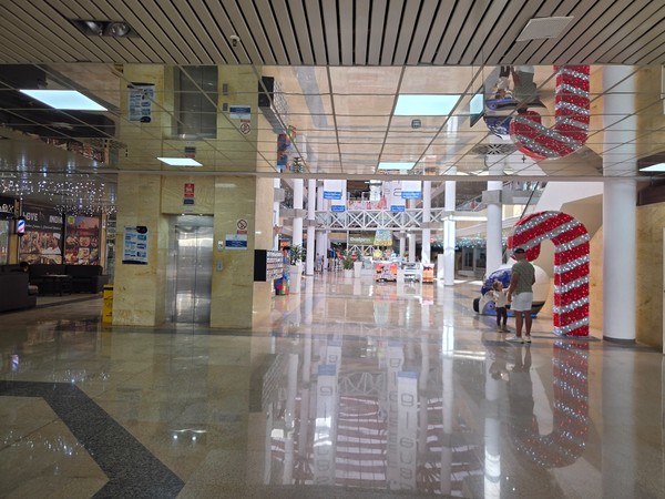Wide corridor inside Pasarela Shopping Center with shiny floors, lift access and families walking between shops and attractions.
