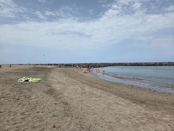 People walking along Playa El Bobo’s sandy shore