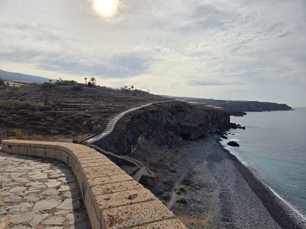 Panoramic view of Playa Aguadulce from the mirador, showing the cliffside path, stepped terraces and the pebble beach along the Atlantic.