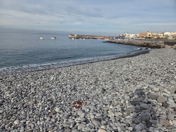 View toward Playa San Juan with anchored sailboats and the harbor in the background seen from the pebble beach.