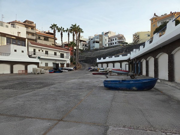 Small blue boats and trailers stored beside the muelle in Alcalá.