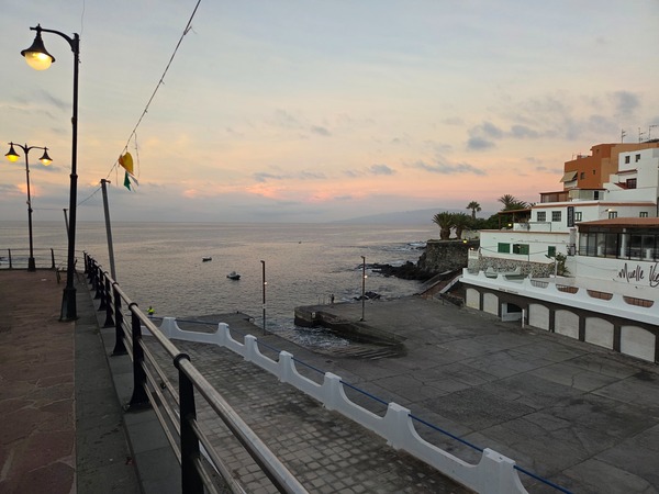 Open paved platform of the Alcalá muelle with the village houses on the lava cliffs.