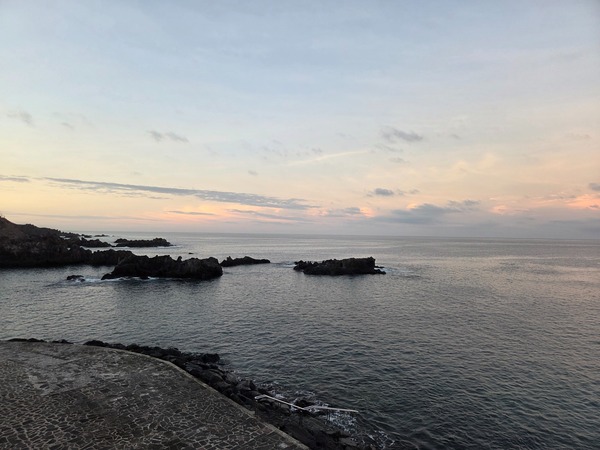 Wide evening view over the rocky coastline of Alcalá with islets and calm Atlantic water.