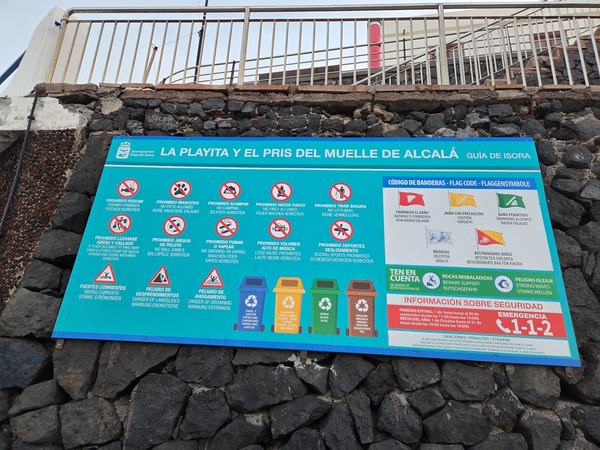 Information board for La Playita and the Pris del Muelle de Alcalá with flag codes and safety icons.