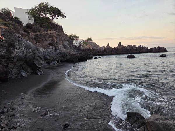 Compact black-sand cove at La Playita in Alcalá with gentle shore break and lava cliffs.