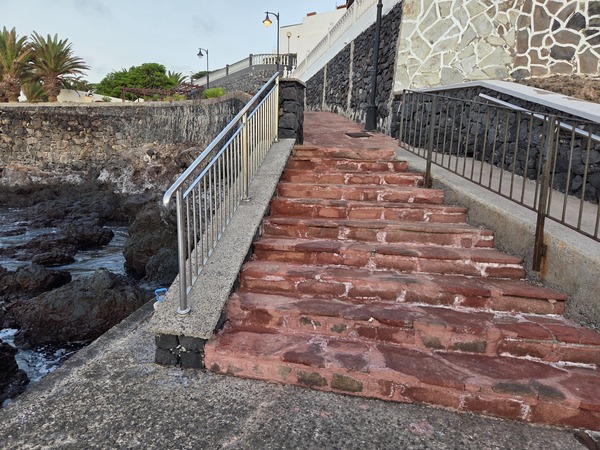 Red stone steps and safety railings connecting the lower platform with the upper promenade in Alcalá.