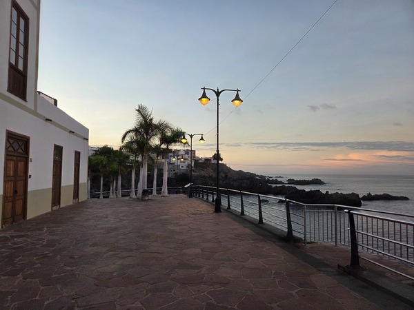 Terrace along the seafront promenade in Alcalá with classic street lamps and ocean views at dusk.