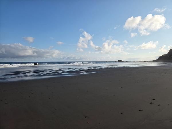 Waves washing over fine black sand at Playa de Almáciga.