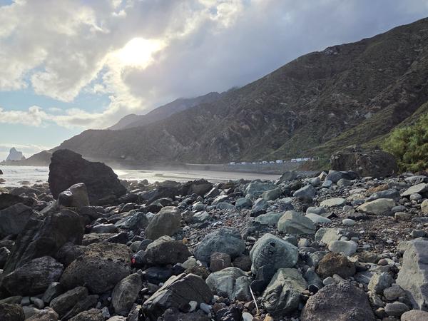 Large coastal rocks and dramatic cliffs near Playa de Almáciga with ocean mist.
