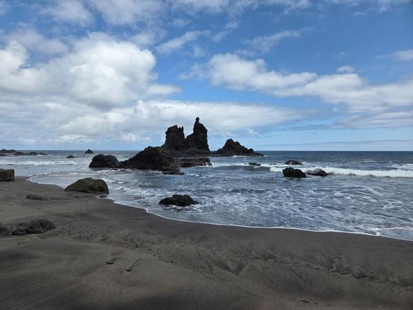 Close-up view of jagged rock formations emerging from the sea at Playa de Benijo under cloudy skies.
