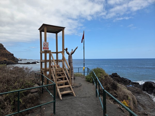Wooden lifeguard tower with a red flag flying, signalling strong currents at Playa El Bollullo.
