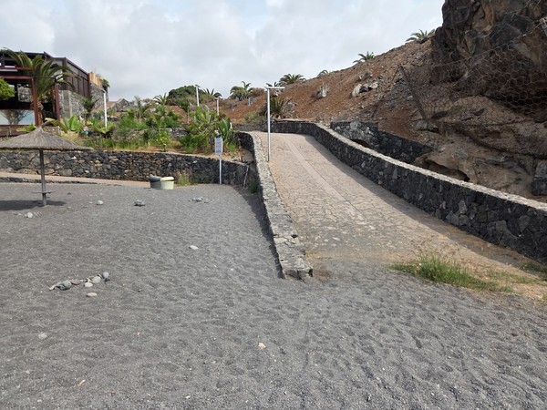 Paved ramp with stone walls providing easy access down to Playa de Ajabo’s black-sand beach.
