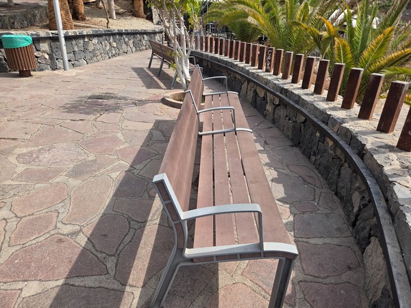 Curved row of benches on the stone-paved promenade overlooking Playa de Ajabo.