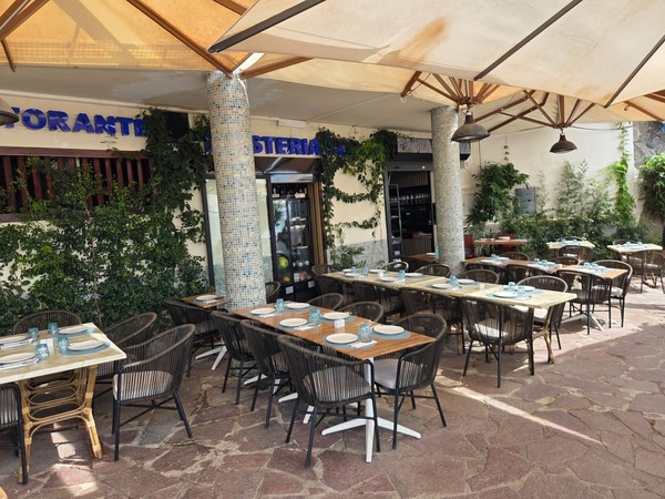 Terrace of a seafront restaurant near Playa de Ajabo with shaded tables set for service.