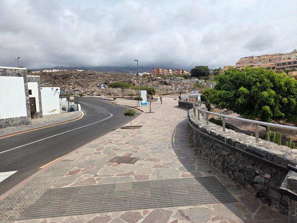 Central wooden walkway across the black sand at Playa de Ajabo leading toward the water and lifeguard post.
