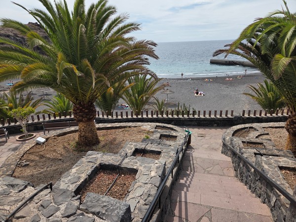 Wide promenade and sidewalk above Playa de Ajabo with stone walls and views toward the coast.