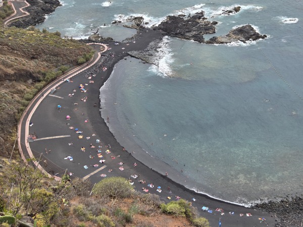 Panoramic view of Playa de la Arena in Tacoronte with its curved black-sand bay, protective rocks and a buoyed swimming zone near Mesa del Mar, Tenerife.