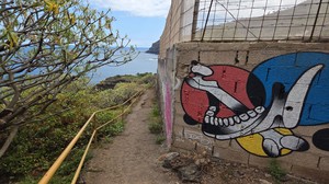 Graffiti art of a jawbone on a wall beside a coastal trail near Playa El Ancón.