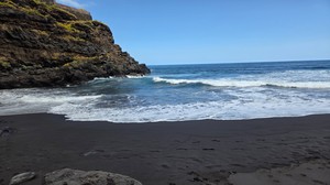 Wave breaking at the edge of the black sand at Playa El Ancón.