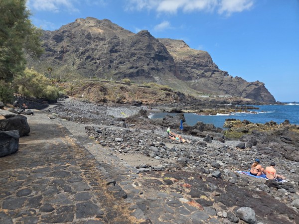 Stone path leading visitors along Playa de Las Arenas with the Teno cliffs rising ahead.