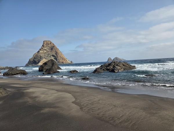 Atlantic waves breaking near Playa de las Breñas with the conical Roques de Anaga offshore.