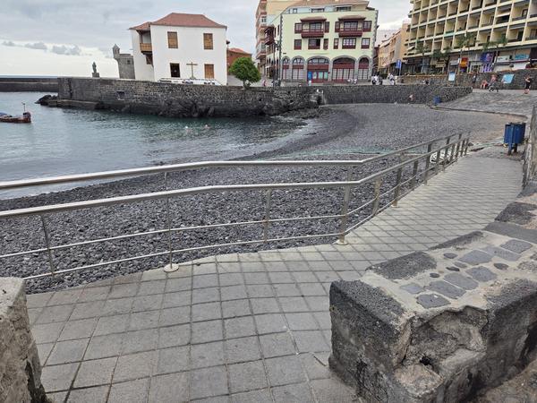 Modern ramp with railings leading down to the pebbled Playa del Muelle beach in Puerto de la Cruz.