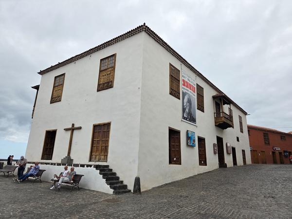 Historic white building with wooden shutters known as Casa de la Aduana, located next to Playa del Muelle.