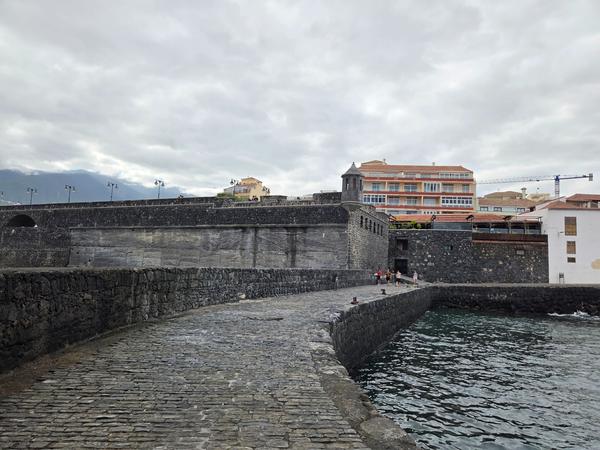 Stone walkway and fortress walls surrounding Playa del Muelle.