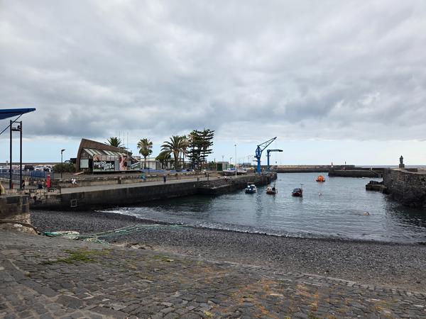 View of the small port with anchored boats and swimmers near Playa del Muelle.