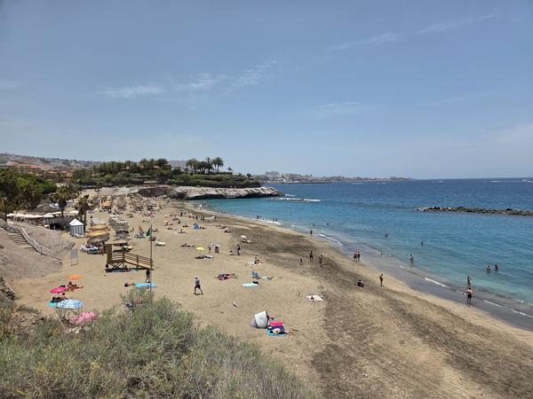 Wide-angle view of Playa del Duque with golden sand and sunbathers.